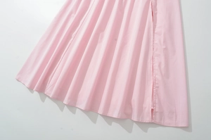 Detail of pink pleated hem showing fine stitching and soft fabric texture on dress