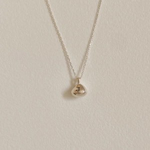 Minimalist 925 sterling silver necklace with J-engraved teardrop pendant on white surface