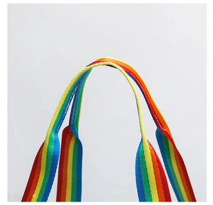 Detailed close-up of the colorful rainbow woven handle on a clear PVC tote bag