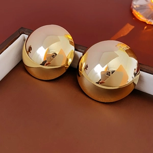 Macro detail of large gold dome earrings with a high-polished mirror finish and sleek design