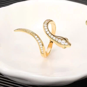 Hip hop style gold snake ring with zircon stones on a white ceramic dish