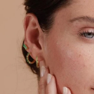 Close-up of gold S925 silver studs featuring three asymmetric green zircon stones