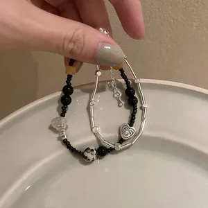 Detalle de pulsera de cuentas con perlas negras, mármol y colgante de corazón en plato