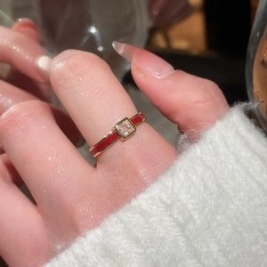 Detail of red enamel gold ring with square zircon stone worn on a finger