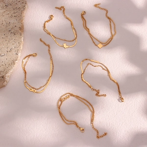 Detail showing five gold double-layer bracelets with love, infinity and map charms
