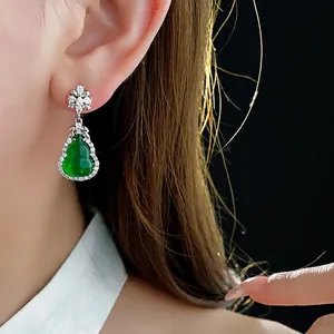 Elegant emerald green gourd earrings with cubic zirconia inlay on a dark background
