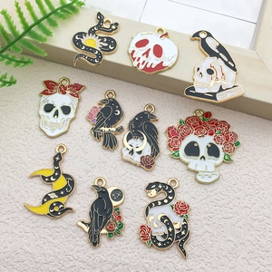 Flat lay of gothic enamel charms featuring skull, snake, moon and rose for DIY jewelry