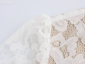 Close-up of elegant white floral lace texture with intricate mesh and nude lining