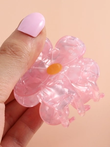Detailed close-up of pink acetate flower hair claw clip with marble texture and yellow center