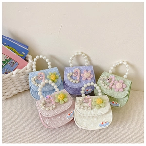 Detail of kids crossbody bags with pearl handles and heart rhinestone decorations
