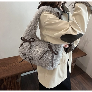 Close-up of grey faux fur shoulder bag featuring leather bows and butterfly ornament