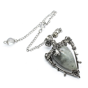 Macro shot of silver metal pendant featuring labradorite stone and carved skull details