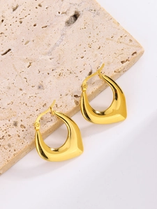 Detail view of 18K gold plated oval hoop earrings resting on a natural stone block