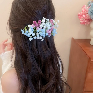 Detail of floral acrylic hair clip with pink blue flowers on wavy brown hair