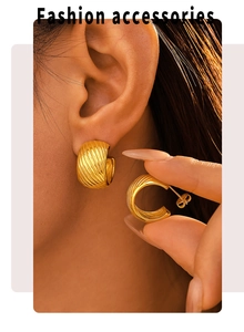 Close-up of gold C-shape hoop earrings with spiral texture on female model's ear