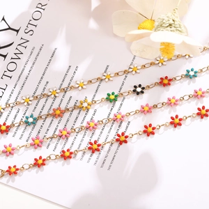 Detailed shot of colorful enamel daisy charms on thin golden chains with floral accents