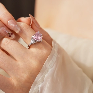 Close-up of pink heart gemstone ring with small diamonds on silver metal band