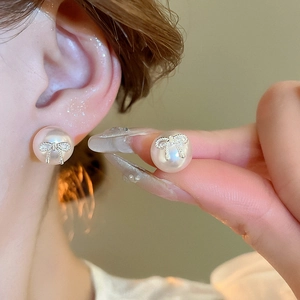 Elegant bow-knot faux pearl earrings on a model's ear for a sophisticated jewelry look