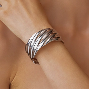 Close-up of metallic silver wavy cuff bracelet on wrist showing glossy liquid textures