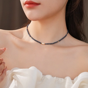 Detailed macro view of a vintage titanium necklace with dark blue beads and a single pearl
