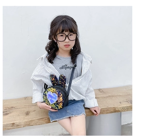 Sequin rabbit ear crossbody bag shown on child model sitting on a wooden bench