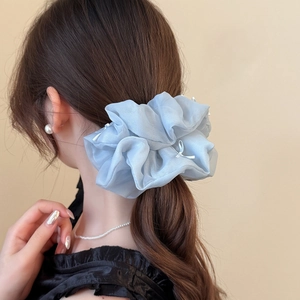 Detail of light blue mesh scrunchie with white bows worn on a ponytail for soft styling