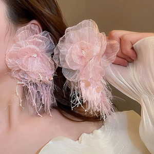 Close-up of pink layered organza flower tassel earrings worn by a model in warm light