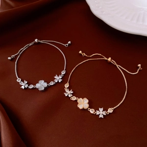 Detail of adjustable gold and silver bracelets featuring white cat-eye stone clover pendants