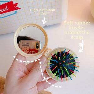 Dettaglio della mini spazzola per capelli pieghevole con specchio interno e setole colorate