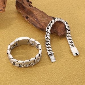 Detail of vintage silver Cuban link bracelets on textured background with wood accent