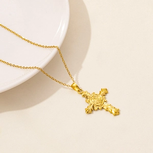 Detail of gold rose cross necklace on white ceramic tray with soft lighting