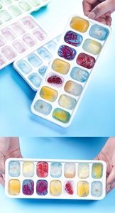 Detail of 14-grid ice cube tray with fruit and flowers frozen inside flexible silicone