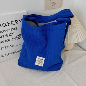 Detail of Klein blue pleated canvas tote bag texture against a minimalist interior background