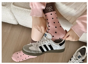 Detailed view of pink polka dot socks with brown bow decoration and sneakers