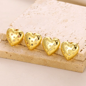 Macro shot of heart-shaped gold studs with colorful zircons on stone base