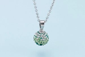Macro shot of silver ball pendant with green gradient rhinestones on chain