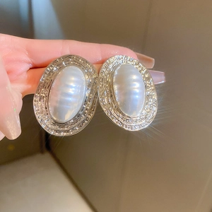 Macro view of vintage oval pearl earrings with hammered silver texture and star flare