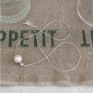 Minimalist S925 sterling silver pearl pendant necklace on a rustic linen background