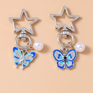 Detail of blue enamel butterfly keychains with rhinestones and white pearls on star clasp