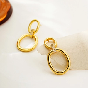 Detail of 18K gold double oval hoop earrings with sparkling zircon accents on soft card