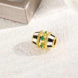Macro detail of oval gold bead with green stone and black-white enamel stripe patterns