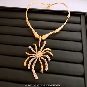 Collier à pendentif fleur dorée avec cristaux clairs sur boîte de présentation noire