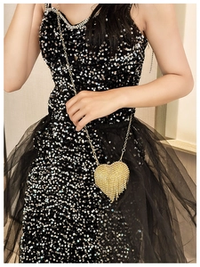 Close-up of golden heart-shaped mini bag with sparkling rhinestones and metal tassels
