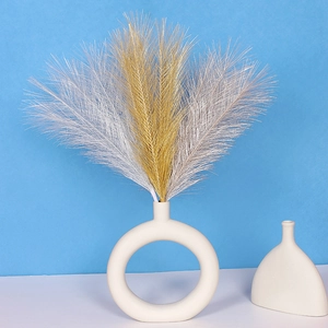 Detail of gold and silver faux pampas grass plumes in a beige circular vase