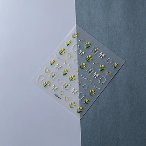 Macro detail of 5D embossed nail stickers with yellow tulips and 3D white bows