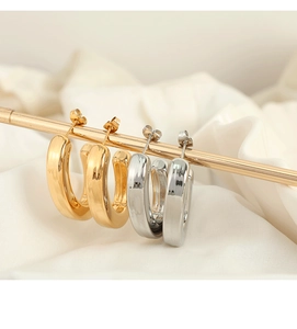 Polished C-shape hoop earrings in gold and silver finish displayed on silk