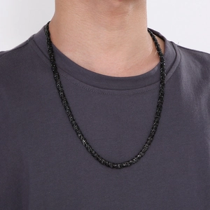 Close-up of black braided rope chain necklace on model wearing a grey t-shirt