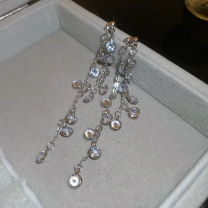 Macro shot of silver drop tassel earrings with sparkling round cubic zirconia stones