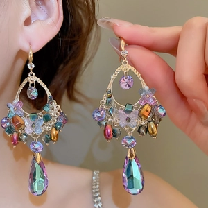 Close-up of dangling drop earrings with colorful crystals and intricate gold filigree
