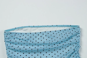 Détail du tissu bleu ciel à pois avec fronces latérales et texture plissée sur la robe
